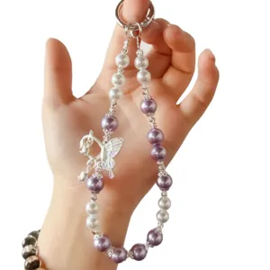 Pearl phone lanyard keychain with purple beads and butterfly charm held by hand main view.