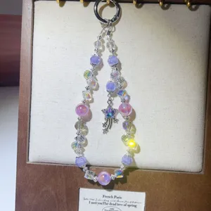 Close-up of handmade crystal beaded phone charm with pink and purple beads and star pendant.
