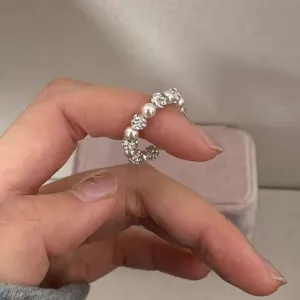 Detail shot of a Korean style stretch pearl and crystal ball ring worn on a finger.