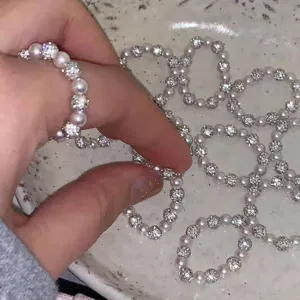 Detail shot of sparkling zircon ball and pearl elastic ring, delicate hand display.