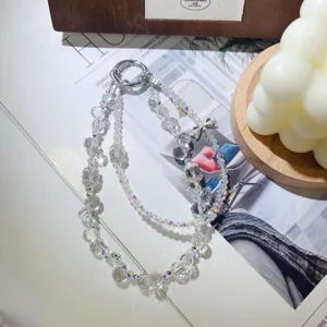 Vue détaillée du charm de téléphone en perles de cristal fait main avec papillon scintillant.