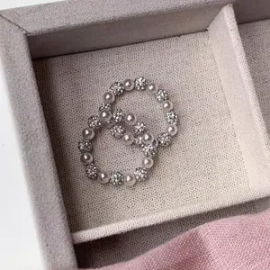 Close-up detail shot of elastic pearl and shimmering crystal ball ring in a jewelry tray.