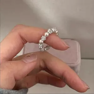 Close-up view of sparkling zircon ball and pearl elastic ring, Korean chic detail design.