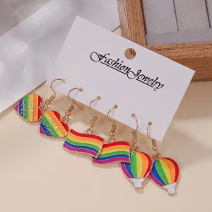 Detailaufnahme von 3 Paaren bunten Emaillierten Regenbogen Herz Flagge Heißluftballon Ohrringen.