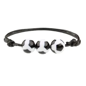 Vista dettagliata del bracciale con cordino nero e perline a forma di pallone da calcio.