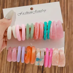 Closeup view of colorful C-shaped resin hoop earrings set displayed on a white paper card.