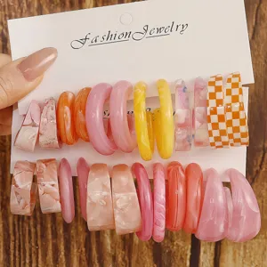 Detailed view of vibrant colorful resin C-shaped hoop earrings displayed on white card.
