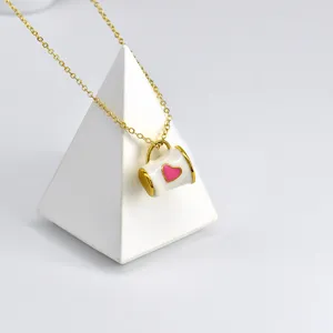 Gros plan détail du collier pendentif mini tasse mignon avec cœur rose en finition or.
