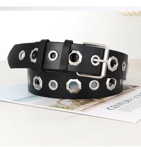 Detailopname van zwarte lederen riem met metalen oogjes en gesp voor damesjeans.