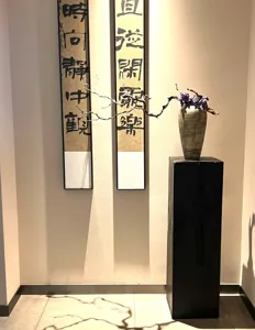 Wabi-sabi style dark solid wood block display stand detail view in minimalist hallway.