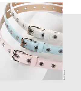 Close-up detail of candy color thin leather belts with metal eyelets and silver buckles.