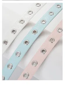 Close-up of candy color thin belts with metallic eyelets and snakeskin texture design.