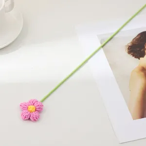 Fleur bouffante en laine tricotée à la main avec tige verte pour décoration de bureau.
