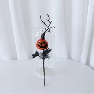 Detailed shot of Halloween decorative pumpkin branch, featuring smiling pumpkin head and black branches.