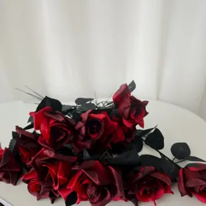 Gros plan détail de roses gothiques artificielles rouge foncé avec feuilles noires.