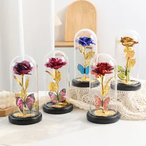 Cupola di vetro di rosa in foglia d'oro con luce LED e decorazione di farfalla, ornamento.