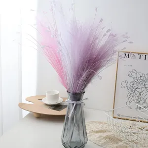 Colorful artificial pampas grass in glass vase for home decor and indoor scene detail.