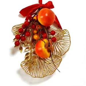 Festive hanging ornament featuring gold leaves, red berries, and persimmon for decor.