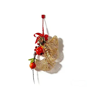 Chinese New Year hanging pendant decoration with golden ginkgo leaves and red lucky fruit for home.