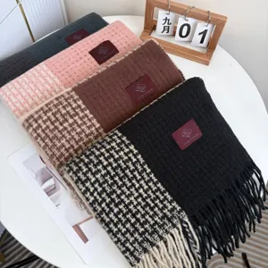 Vue détaillée d'écharpes à carreaux épaisses avec franges et étiquettes sur table.