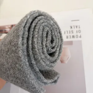 Gray knit scarf detail close up showing soft wool texture and rolled winter fashion design.