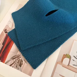 Detailed shot of dark blue knitted cross neck warmer, soft wool texture winter accessory.