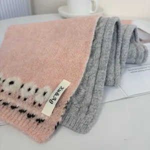 Vista dettagliata di una elegante sciarpa in maglia misto lana jacquard bicolore per l'inverno.