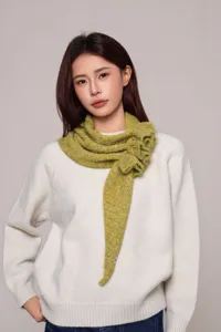 Close-up detail of the green textured knit shawl with stylish ruffle design worn on model.