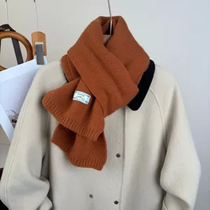 Primo piano della sciarpa in maglia marrone accogliente con texture morbida e bella etichetta.