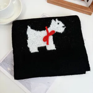 Detailed view of black knit scarf with white cute animal and red bow decoration.