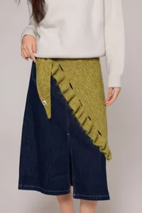Close-up detail of a stylish knitted ruffle shawl wrap layered with a cozy sweater and denim.