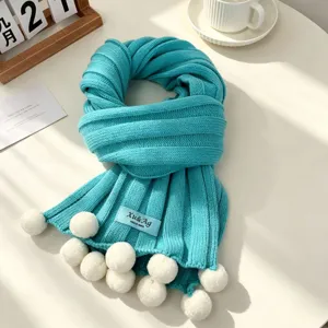 Cozy turquoise knit scarf featuring playful white pom-poms and ribbed texture detail.