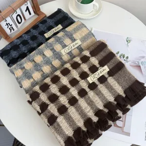 Detailed shot of cozy winter plaid cashmere-feel scarf, chic checkered pattern with fringe.