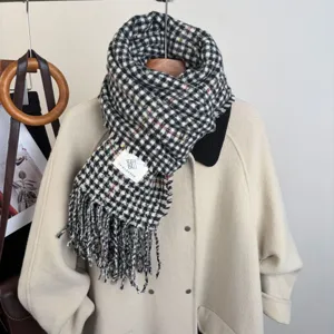 Classic black and white houndstooth scarf detail showing soft textured fabric and fringe edge.