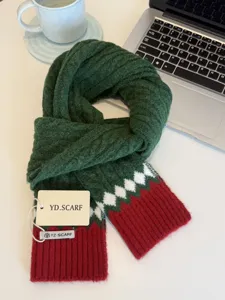 Close-up detail of the cozy green knitted winter scarf featuring festive red and white patterns.