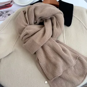 Primo piano della morbida sciarpa in maglia beige, trama fine e stile autunno inverno caldo.