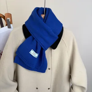 Primo piano della sciarpa in maglia blu accogliente sul cappotto, consistenza morbida.