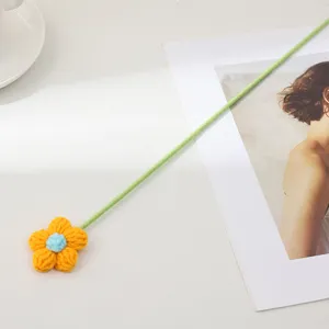 Détail de fleur bouffante au crochet faite main avec tige verte pour déco de bureau.