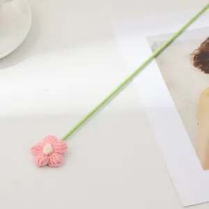 Gros plan d'une fleur rose tricotée à la main avec une longue tige verte pour la déco.