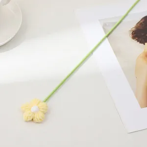 Gros plan de fleur tricotée jaune artisanale à tige verte, détail déco élégant.
