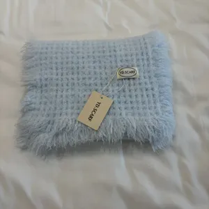 Light blue knitted scarf detail showing cozy handmade fringed winter neck warmer.