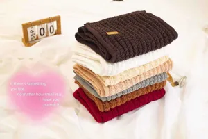 Detailed view of stacked cozy knit scarves in various colors, soft wool winter neck warmer.