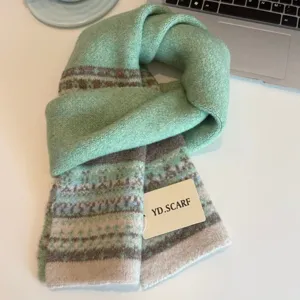 Detail view of a Nordic style mint green knitted winter scarf with geometric patterns and tag.