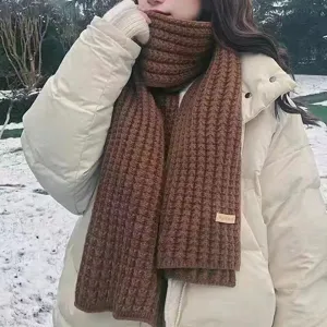 Detail view of the brown knitted winter scarf worn outdoors in snow, soft winter accessory.