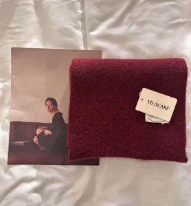 Soft burgundy knitted scarf detail shot showcasing cozy plush texture and branded paper tag.