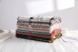 Detailed shot of stacked mohair plaid and solid scarves, showing soft texture and cozy warmth.