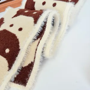 Primo piano di una sciarpa in maglia con motivo gatto stile giapponese marrone beige.