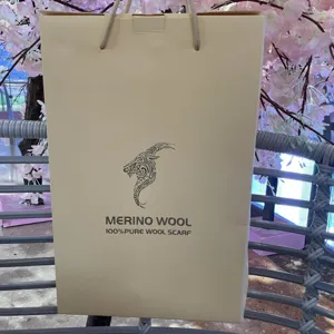 Primo piano di una borsa regalo di carta per sciarpa in lana merino con logo ariete.