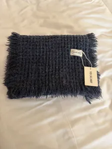 Dark grey knitted fringed winter scarf detail shot, warm and cozy solid color neck wrap.