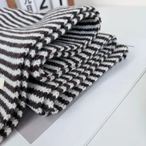 Detailed view of brown white striped knit scarf, soft warm winter accessory for cold days.